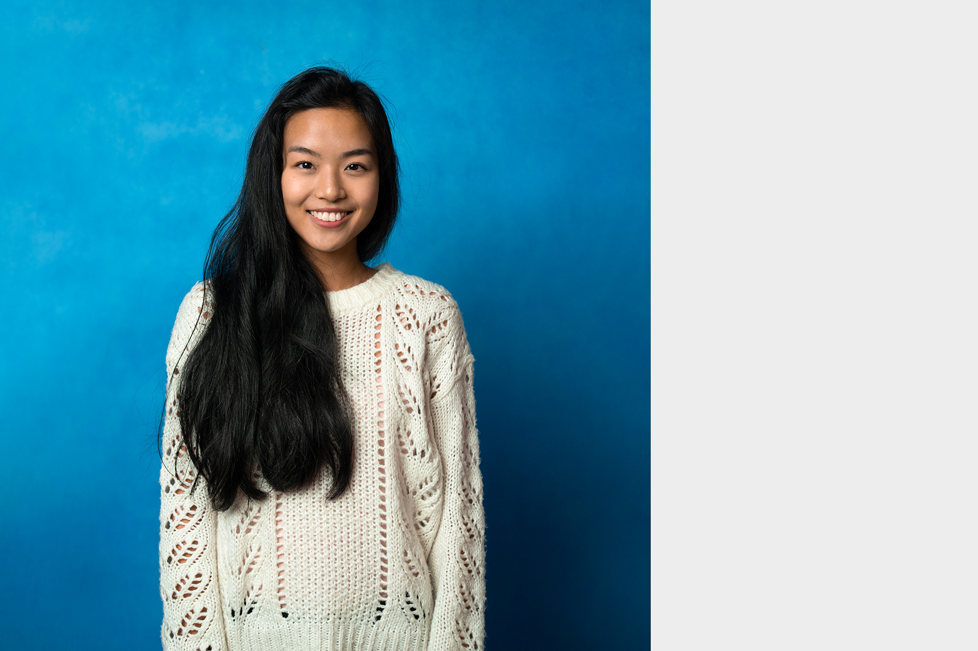 Hoang, studio portrait of young female volunteer in front of blue background